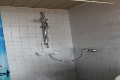 Moderne douche met witte tegels en verstelbare douchekop, gefotografeerd bij lodge «Am Strand» in Duitsland.