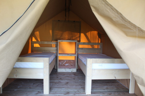 Vista interna di una tenda safari con due letti singoli al Campeggio La Colline in Belgio, pavimento in legno.