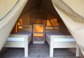 Vista interior de una tienda safari con dos camas individuales en el camping La Colline en Bélgica.