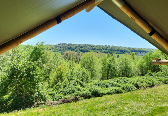 Vista desde una tienda safari en el Camping La Colline en Bélgica, con abundante vegetación y colinas.