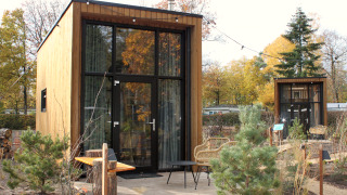 Een modern tiny house, Tiny Community 16, bij De Hooge Veluwe in Nederland, omringd door bomen en tuin.