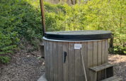 Buitenhouten hottub met deksel en trapje bij Tiny Community 16, De Hooge Veluwe, Nederland in het voorjaar.