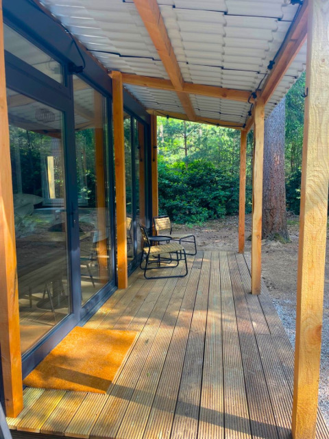 Houten terras en stoelen aan Forest Cabin bij Outdoors Holten, omringd door bos in Nederland.