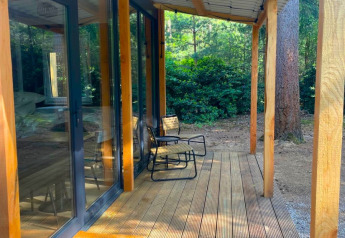 Houten terras en stoelen aan Forest Cabin bij Outdoors Holten, omringd door bos in Nederland.