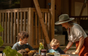 Famiglia fa colazione a un tavolo davanti alla tenda safari De Stille Heide con stufa e vasca calda.