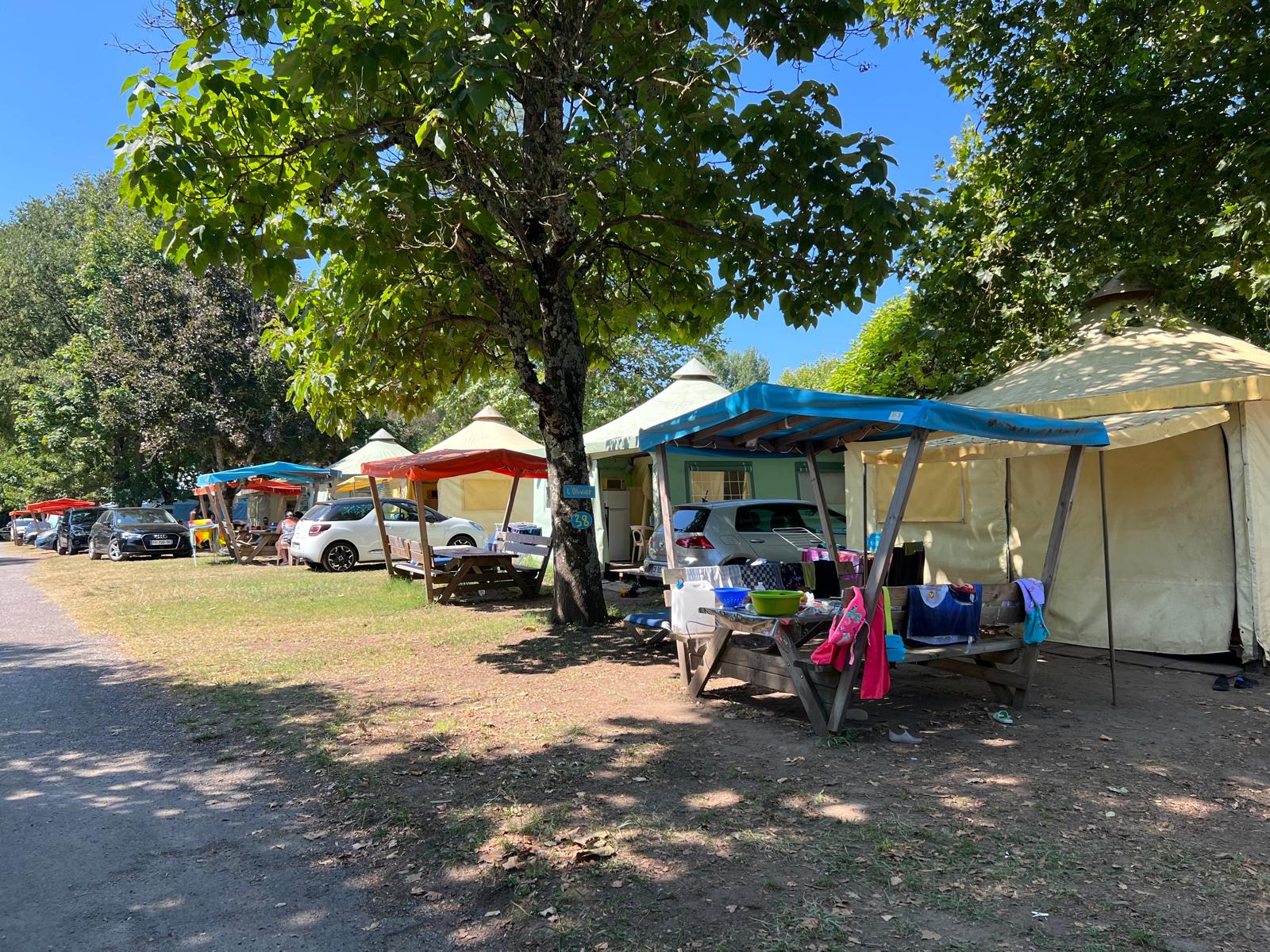 Safaritenten met auto's en kleurrijke overkappingen bij Camping Paradis Family des Issoux in Frankrijk.