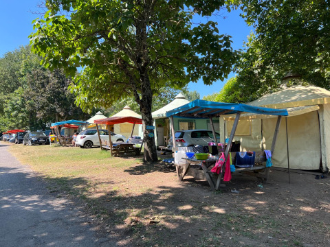 Safaritenten onder kleurrijke zeilen bij Camping Paradis Family des Issoux in Frankrijk, auto's erbij.