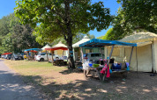 Tiendas safari y autos estacionados en Camping Paradis Family des Issoux, Francia, bajo sol y árboles.