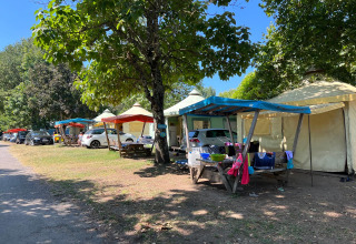 Safaritenten onder kleurrijke zeilen bij Camping Paradis Family des Issoux in Frankrijk, auto's erbij.
