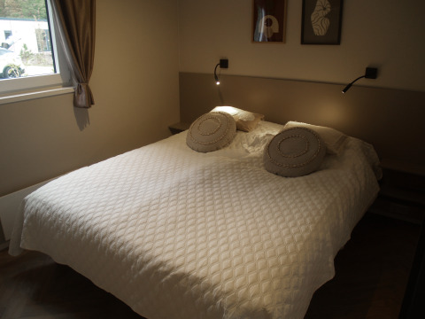Dormitorio en Groeneborg Lodge en Holiday park De Wiltzangh, Países Bajos, con cama doble y ventana.