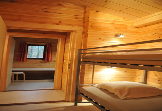 Chambre chaleureuse avec lits superposés et murs en bois dans le chalet “De Boshut” en Belgique.