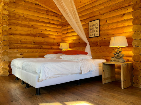 Romantische Holzhütte mit Doppelbett, Holzinterieur und stimmungsvoller Beleuchtung in Outdoors Holten.