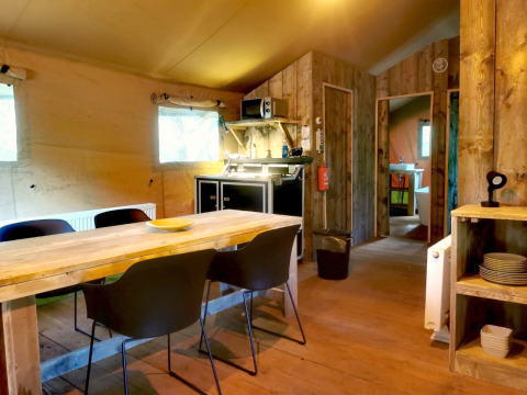 Indretning af safari glamping telt med spisebord, stole og køkken ved Outdoors Holten, Nederlandene.