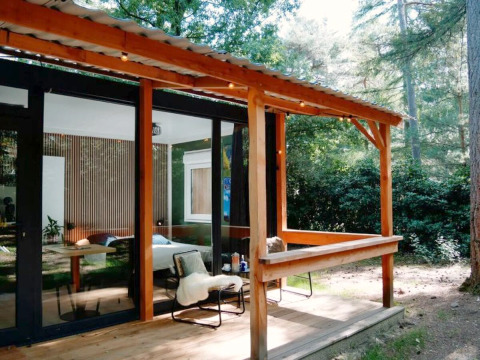 Wooden cabin with covered porch set in a forest at Forest Cabin, Outdoors Holten, Netherlands.