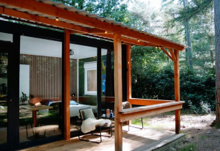 Gemütliche Holzhütte mit überdachter Terrasse im Wald bei Forest Cabin, Outdoors Holten, Niederlande.