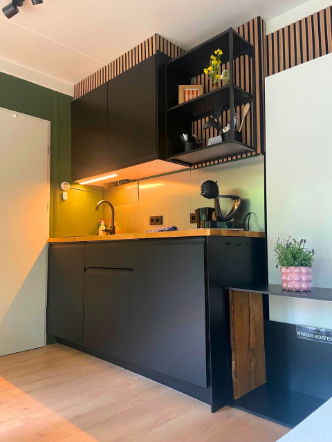 Moderne schwarze Küchenzeile mit Holzarbeitsplatte in der Forest Cabin bei Outdoors Holten, Niederlande.