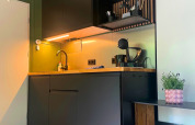 Moderne zwarte kitchenette met houten werkblad in Forest Cabin bij Outdoors Holten, Nederland.