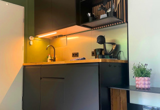 Pequeña cocina moderna negra con encimera de madera en Forest Cabin de Outdoors Holten, Países Bajos.