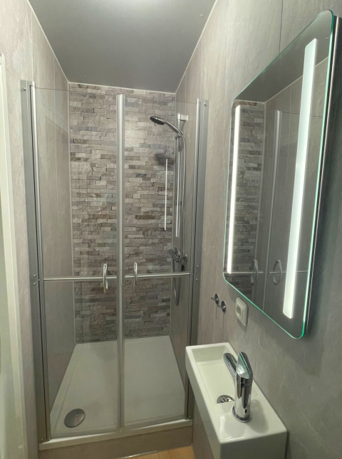 Moderne compacte badkamer in Forest Cabin bij Outdoors Holten, Nederland, met douche en kleine wastafel.