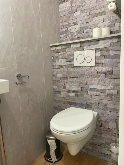 Baño moderno en Forest Cabin de Outdoors Holten, Países Bajos, con inodoro de pared y azulejos grises.
