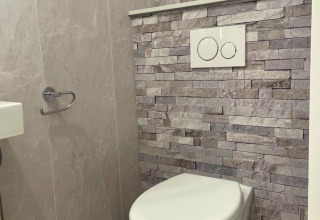Modern toilet in Forest Cabin bij Outdoors Holten, Nederland met wandcloset en stenen achterwand.