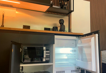 Kompakte Küchenzeile in einer Forest Cabin bei Outdoors Holten, Niederlande, mit offenem Kühlschrank.