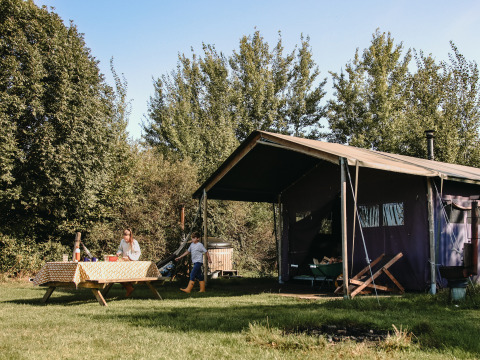 Familia acampando en BoerenBed De Kalverweide, Overijssel, Países Bajos, con tienda y mesa de picnic al aire libre.