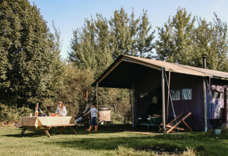 Familia acampando en BoerenBed De Kalverweide, Overijssel, Países Bajos, con tienda y mesa de picnic al aire libre.