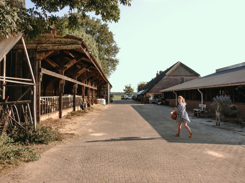 Niña con cesta paseando por BoerenBed De Kalverweide, parque vacacional en Overijssel, Países Bajos.