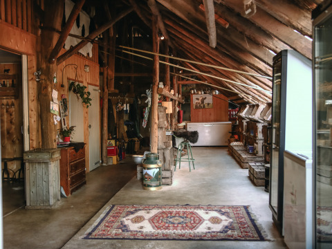 Interior rústico de granero con vigas de madera, alfombra y utensilios en BoerenBed De Kalverweide en Overijssel.
