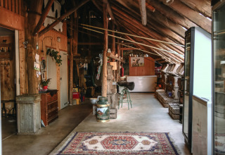 Interior rústico de granero con vigas de madera, alfombra y utensilios en BoerenBed De Kalverweide en Overijssel.