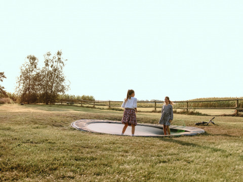 Dos niñas juegan en una cama elástica enterrada en BoerenBed De Kalverweide, Overijssel, Países Bajos.