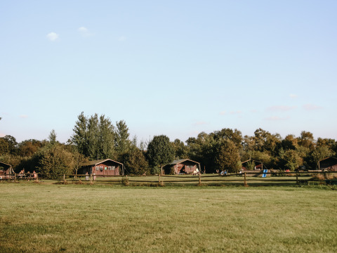 Vista del parque vacacional BoerenBed De Kalverweide en Overijssel, Países Bajos, con cabañas y campos verdes.