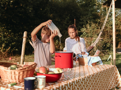 Dos niños cocinan al aire libre con cestas de frutas en BoerenBed De Kalverweide, Overijssel, Países Bajos.