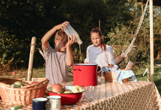 Dos niños cocinan al aire libre con cestas de frutas en BoerenBed De Kalverweide, Overijssel, Países Bajos.