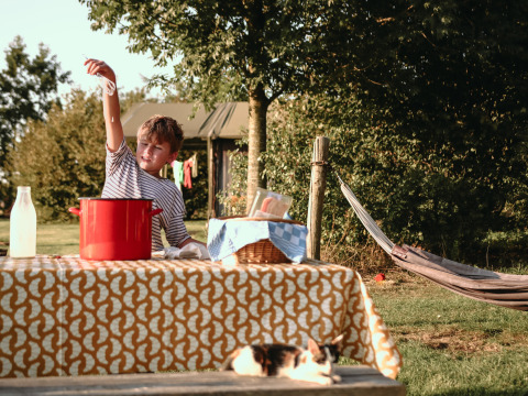 Niño juega en una mesa con una olla roja al aire libre en BoerenBed De Kalverweide, Overijssel, Países Bajos.