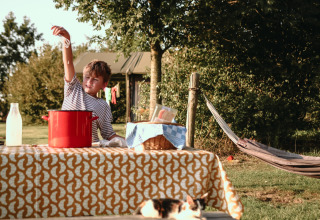 Niño juega en una mesa con una olla roja al aire libre en BoerenBed De Kalverweide, Overijssel, Países Bajos.