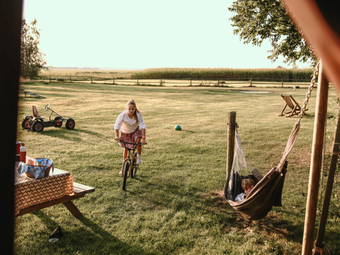 Niños jugando en el césped con bicicleta y hamaca en BoerenBed De Kalverweide, Overijssel, Países Bajos.
