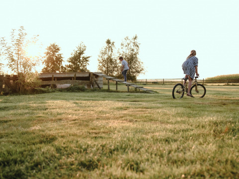 Niños juegan al aire libre al atardecer sobre el césped en BoerenBed De Kalverweide, Overijssel, Países Bajos.