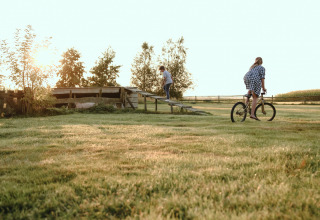 Niños juegan al aire libre al atardecer sobre el césped en BoerenBed De Kalverweide, Overijssel, Países Bajos.