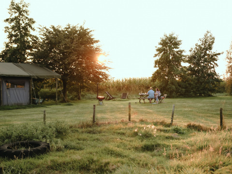 Familia disfruta de un picnic al atardecer en BoerenBed De Kalverweide, parque vacacional en Overijssel, Países Bajos.