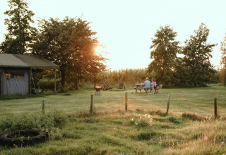 Familia disfruta de un picnic al atardecer en BoerenBed De Kalverweide, parque vacacional en Overijssel, Países Bajos.