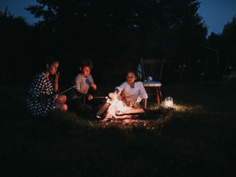 Niños asan malvaviscos en una fogata por la noche en BoerenBed De Kalverweide, Overijssel, Países Bajos.