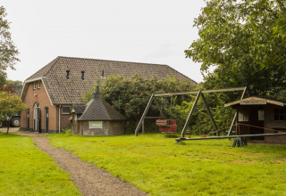 Image of a playground and barn at BoerenBed Het Boshuis holiday park in Gelderland, Netherlands.