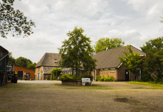 Uitzicht op BoerenBed Het Boshuis vakantiepark in Gelderland, Nederland, met boerderij en bomen.