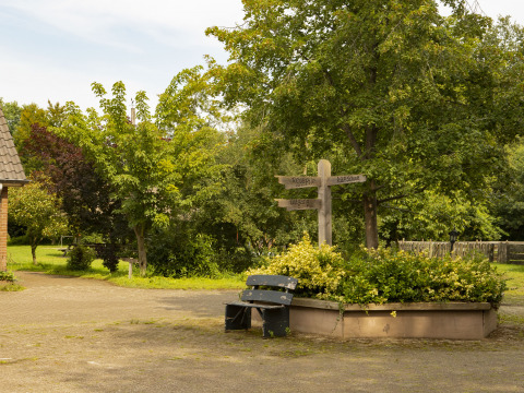 Ein ruhiger Platz im BoerenBed Het Boshuis, Gelderland, mit Wegweisern, Sitzbank und viel Natur.