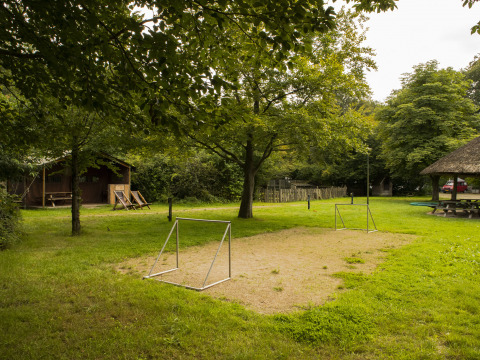 Klein voetbalveldje, picknicktafels en houten hutten in het groene BoerenBed Het Boshuis in Gelderland, Nederland.