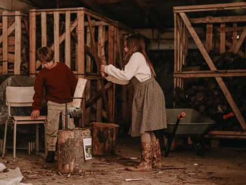 Twee kinderen zijn samen hout aan het kloven in een schuur bij BoerenBed Hoeve den Overdraght in België.