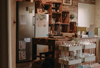 Cozy kitchen area with fridges and glassware at BoerenBed Hoeve den Overdraght, West Flanders, Belgium.