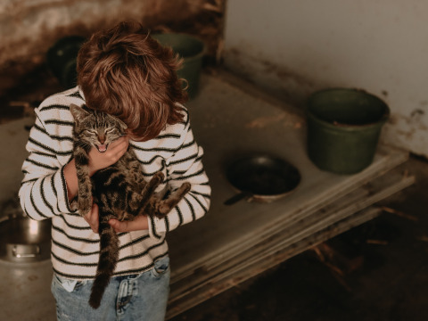 Enfant en pull rayé tenant affectueusement un chat à BoerenBed Hoeve den Overdraght en Belgique.
